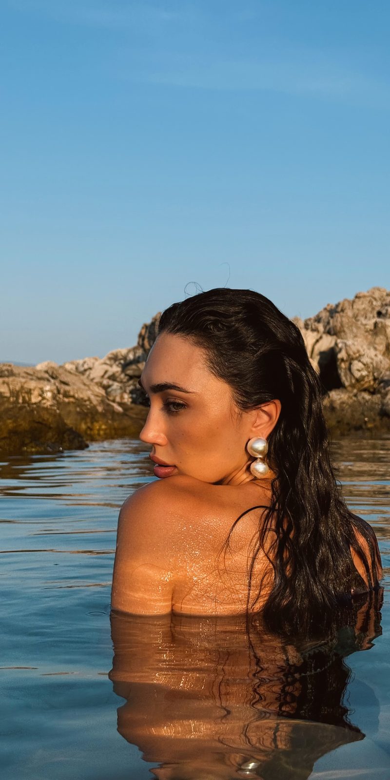Dubravka Švegar u moru do ramena, mokre kose, s bisernim naušnicama, uz stijene